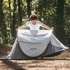 Mężczyzna rozkłada namiot plażowy Quechua. Szybkie rozkładanie namiotu to klucz do udanego wypoczynku.