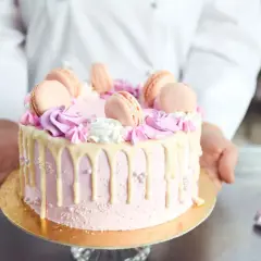 Różowy tort z makaronikami i kremem. Idealne ozdoby do tortu znajdziesz w cukierni.