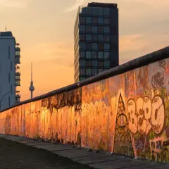 Zachód słońca nad graffiti na pozostałościach Muru Berlińskiego, przypominającego o tym, kiedy został zbudowany mur berliński.
