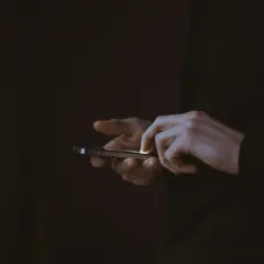 Dłonie użytkownika na ekranie smartfona, być może szukającego informacji, jak zrestartować Messengera.
