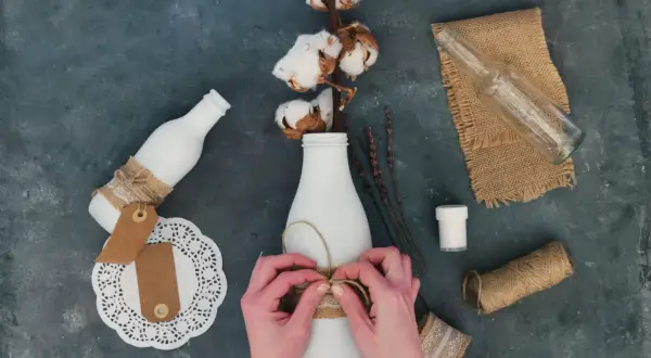 Ręce wiążą sznurkiem butelkę, tworząc ozdobę. Idealne pomysły, co można zrobić na Dzień Chłopaka DIY.