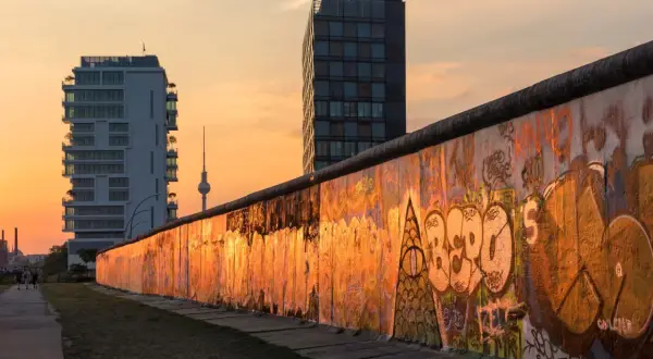 Zachód słońca nad graffiti na pozostałościach Muru Berlińskiego, przypominającego o tym, kiedy został zbudowany mur berliński.