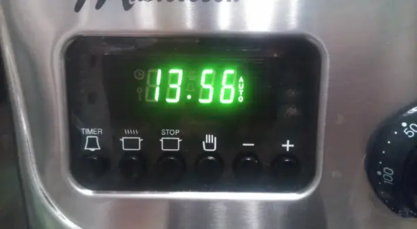 Cyfrowy wyświetlacz piekarnika Mastercook pokazuje godzinę 13:56. Ikony sugerują funkcje timera, gotowania, stopu i automatycznego trybu.